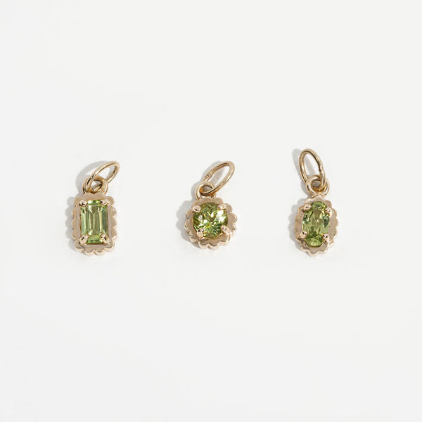 Three 14k gold pendants with green gemstones on a white background